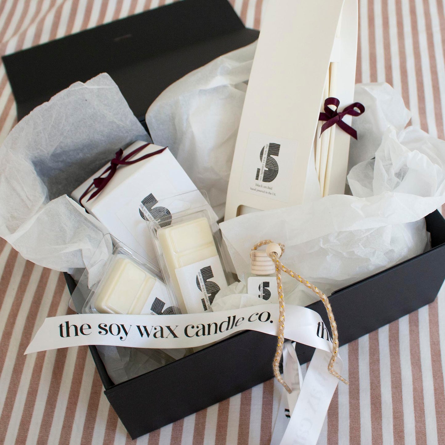 The Soy Wax Candle Company Woody Gift Hamper containing one soy wax candle, one reed diffuser, one car diffuser and 2 soy wax melt bars.  A luxurious gift!