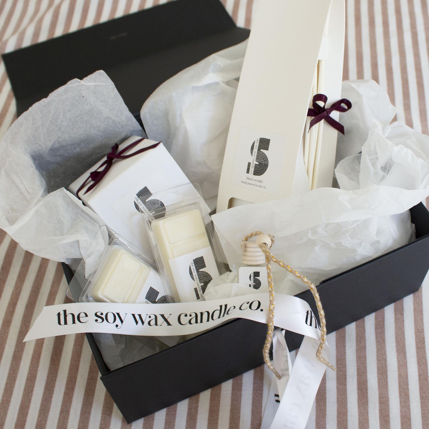 The Soy Wax Candle Company Woody Gift Hamper containing one soy wax candle, one reed diffuser, one car diffuser and 2 soy wax melt bars.  A luxurious gift!